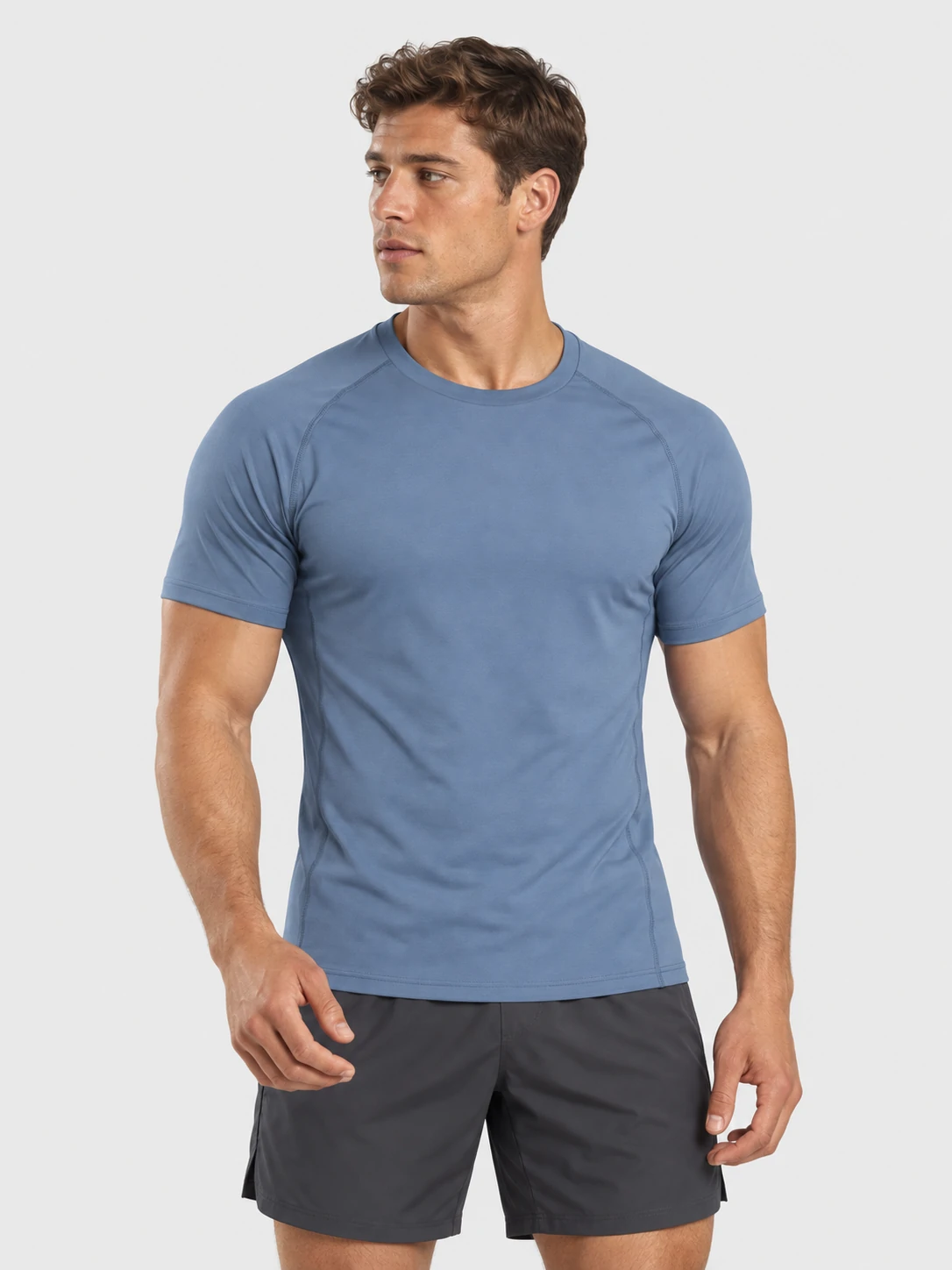 Male fitness model wearing a blue short-sleeve performance gym T-shirt with black training shorts for men’s custom activewear