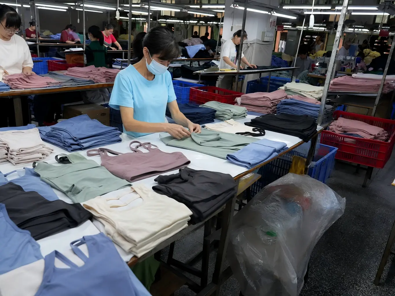 Workers inspecting and organizing sports bras and leggings during activewear manufacturing in a garment factory