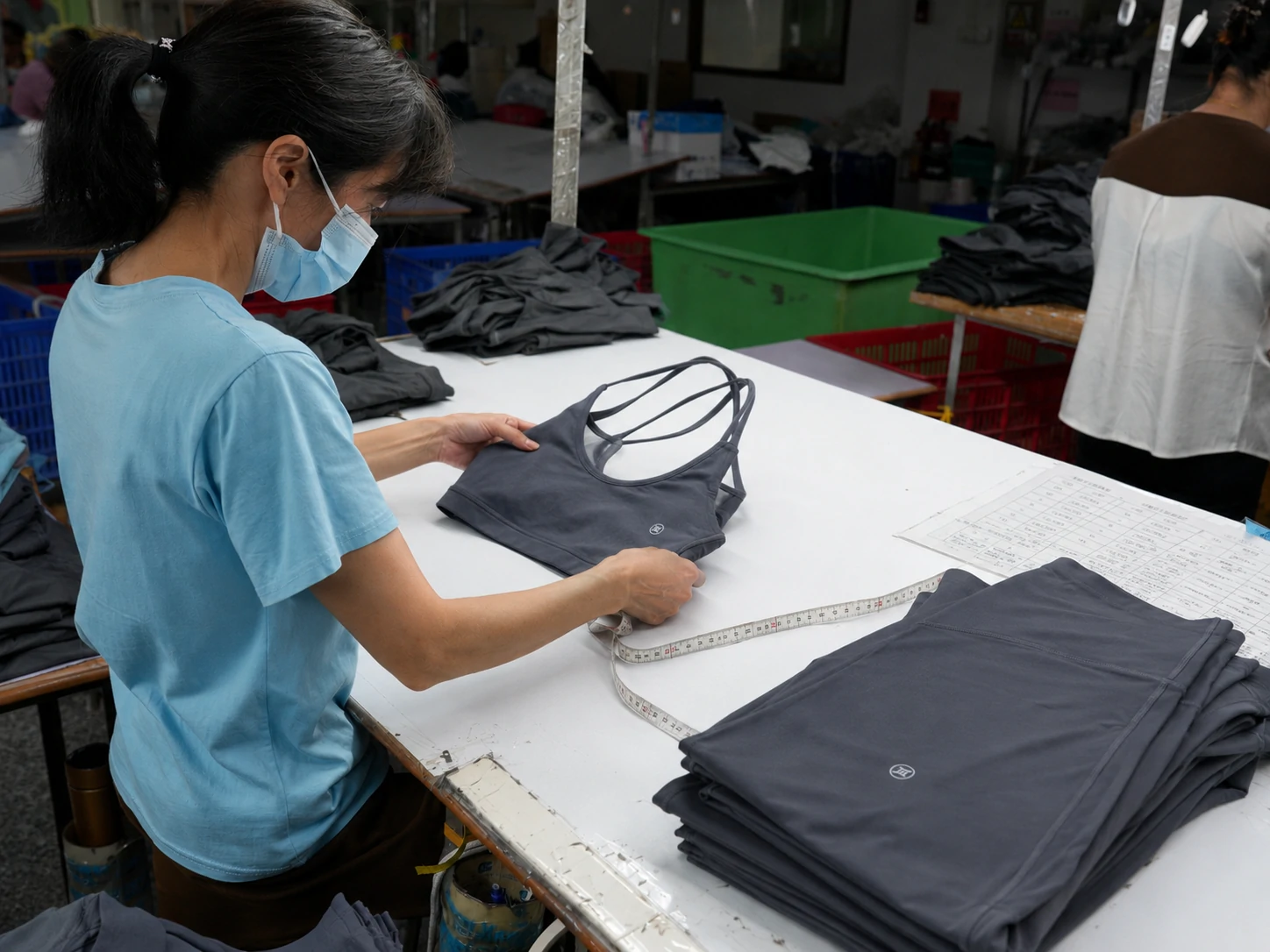 Worker inspecting a sports bra and leggings during quality control at an activewear manufacturing factory