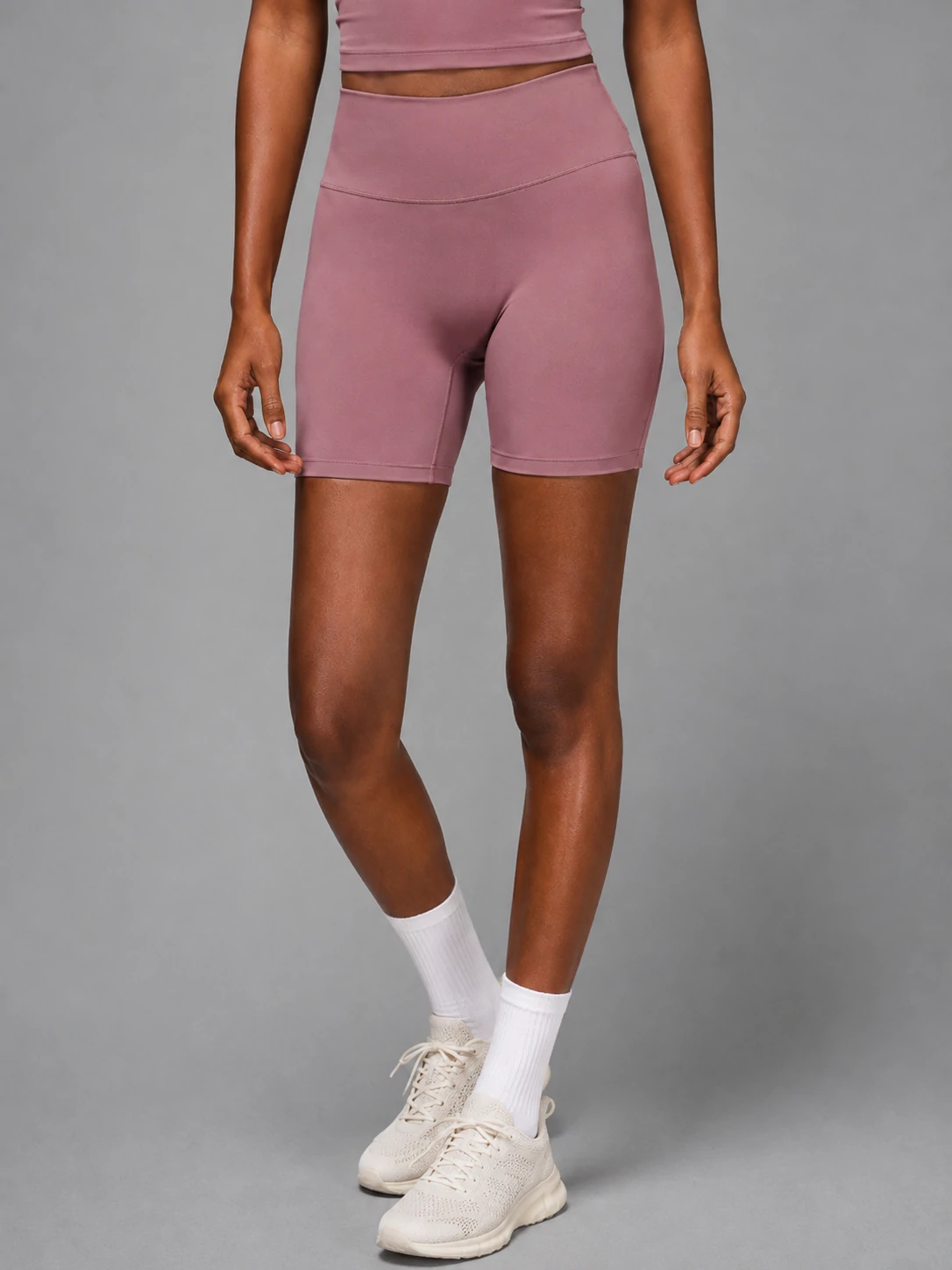 Female model wearing mauve high-waisted gym shorts designed for women’s activewear and fitness training