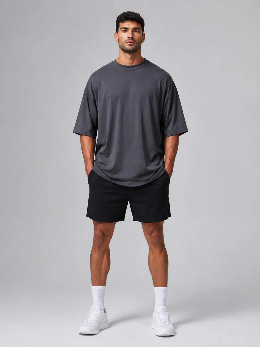 Male fitness model wearing an oversized charcoal gym T-shirt with black training shorts for men’s activewear