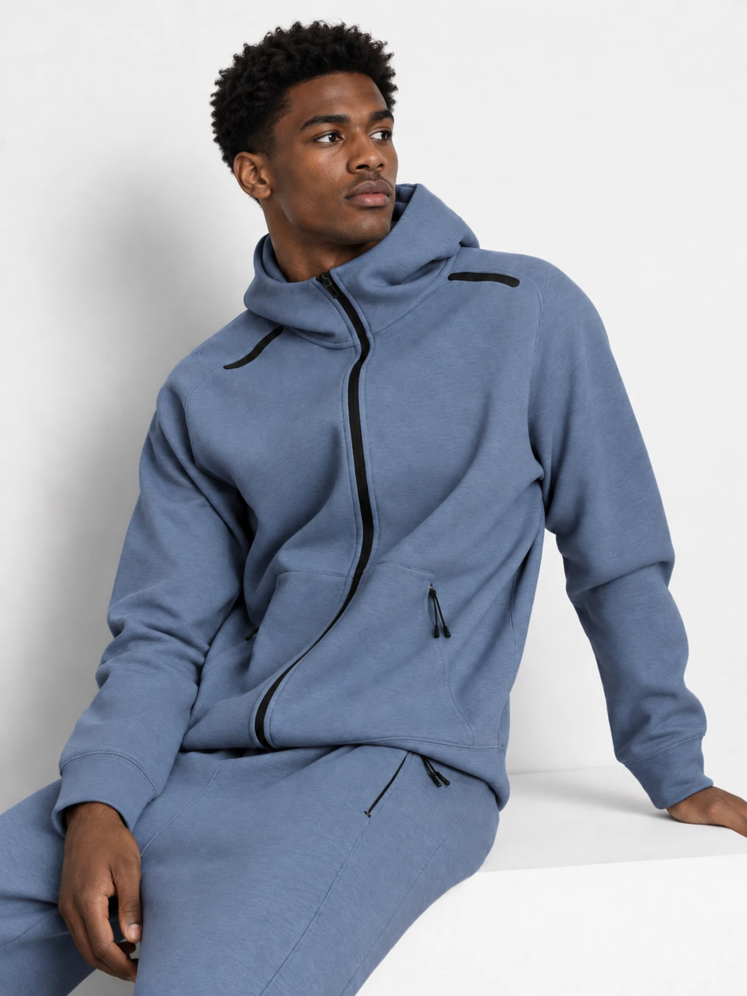 Male fitness model wearing a blue zip-up gym hoodie with matching joggers for men’s custom activewear