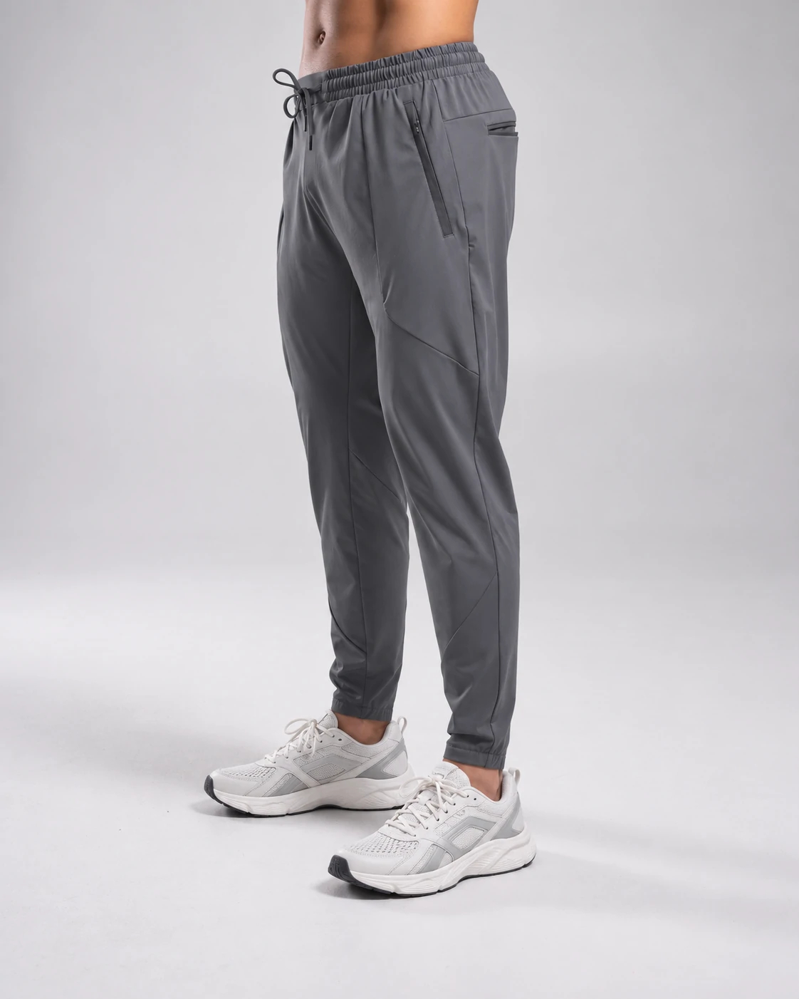 Custom men's gray tapered joggers with drawstring waistband and athletic sneakers